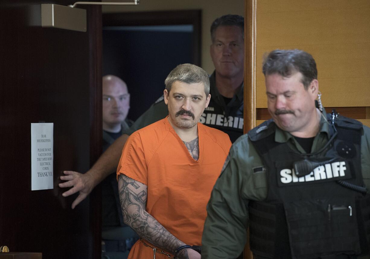 Triple-homicide suspect Brent Luyster is surrounded by law enforcement officials as he makes his way into Clark County Superior Court for the attorneys to discuss discovery issues in his case on Friday morning, Oct. 6, 2017.