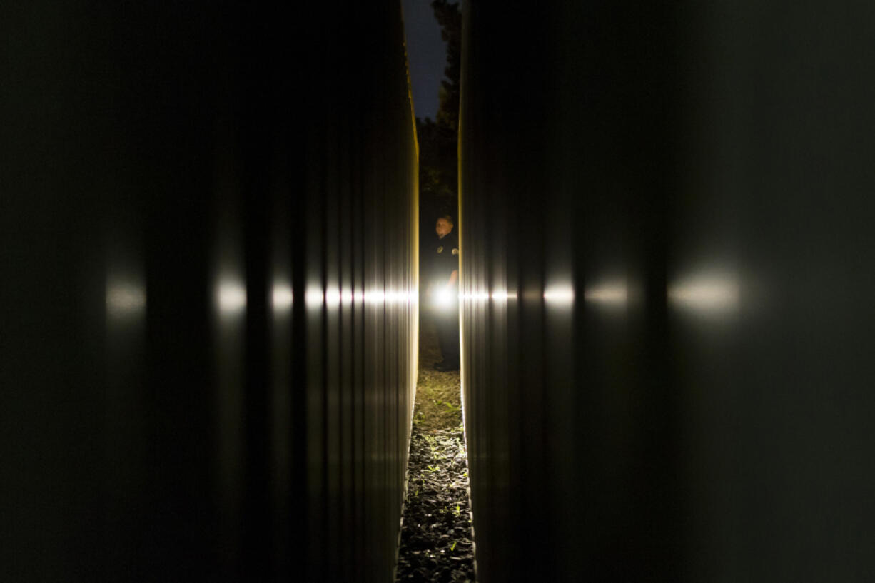 Clark College campus security officer Eben Ayers shines his flashlight between two shipping containers at Clark College. Officers working the night shift patrol the 101-acre campus; these containers in the college’s 23-acre sports complex are often frequented by transients. “There’s a lot of people who just like to migrate, and Clark College is a nice place to be,” Ayers said.