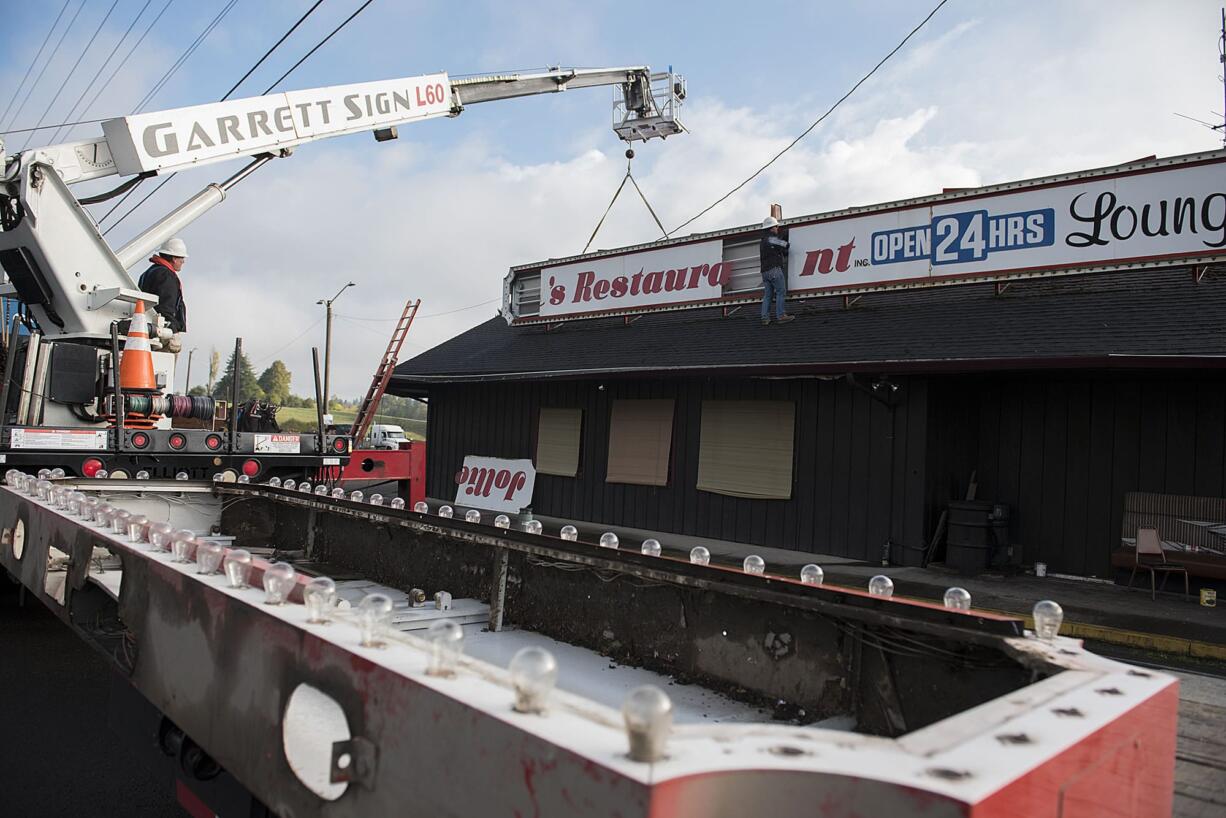 Earl Abercrombie, left, and Caleb Smythe of Garrett Sign work together to remove the front sign from Jollie's Restaurant & Lounge in Ridgefield on Friday morning. The roadside restaurant, which was popular among locals and passing truckers, recently closed its doors after 54 years in business.