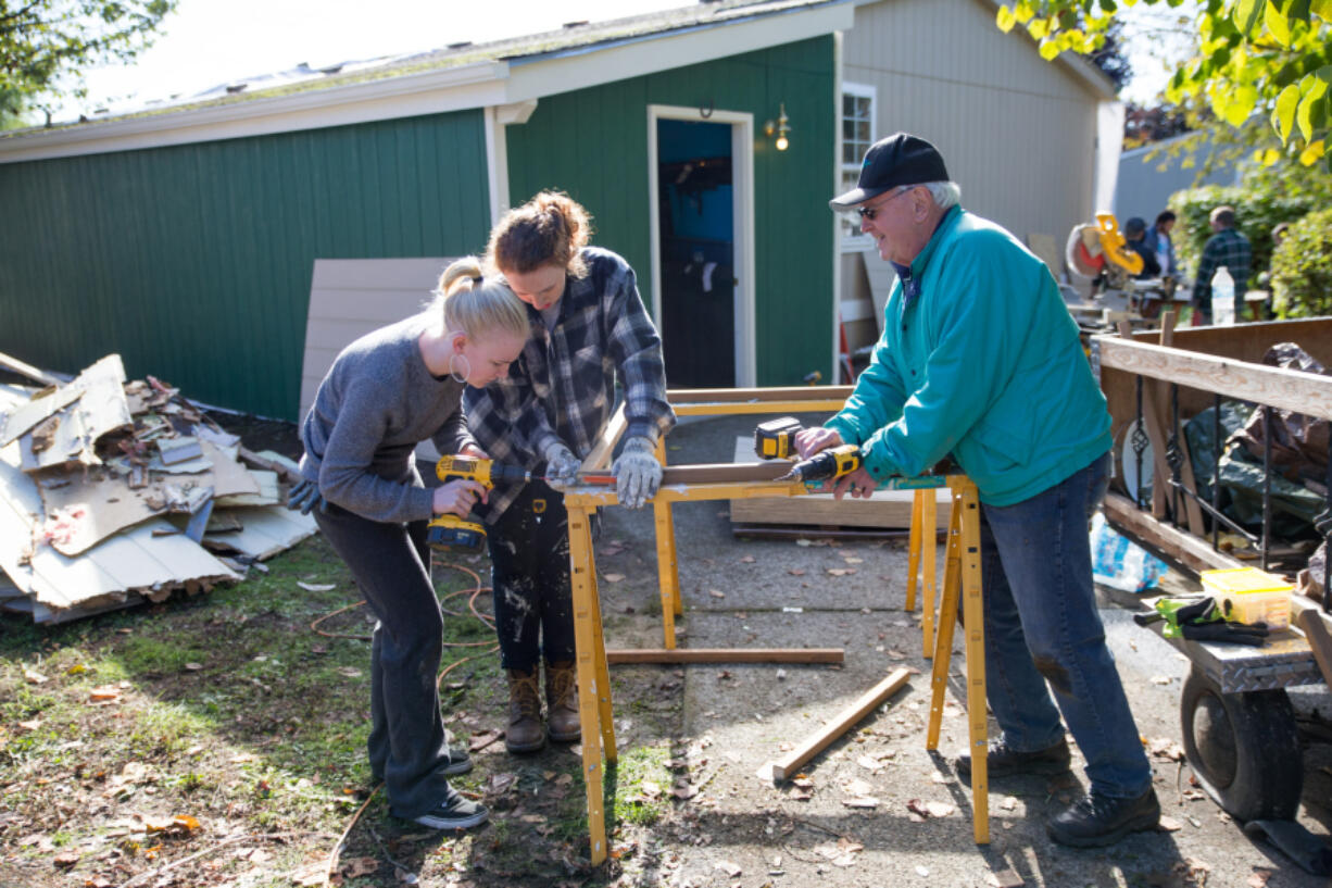 From left to right, Max Alexander and Gwen White, with the Young Democrats of Clark County, and Denny Kiggins, Clark Regional Wastewater District commissioner, construct a skirt for a Washougal mobile home during Evergreen Habitat for Humanity’s Elected Officials Build Day on Saturday. (Randy L.