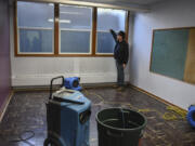 The Rev. Jaime Case points to a waterline on three windows in the basement of St. Luke’s Episcopal Church in west Vancouver. Heavy rains on Thursday caused flooding in a large part of the church’s basement.