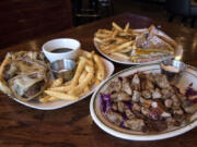 The famous prime rib dip sandwich with a side of french fries, left, the Couve Cristo with a side of french fries, back, and the steak bites, right, at the 99 Saloon & Grill.