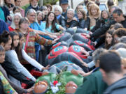 A crowd lays their hands on a totem pole bound for the Carnegie Museum of Natural History Monday evening.