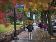 Jose Alvarez walks through rain and falling leaves by the Clark County Courthouse on Franklin Street in Vancouver on Thursday. More rain and wind is expected through the weekend.