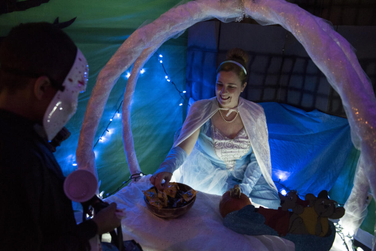 Vancouver’s Nicole Jensen, dressed as Cinderella, hands out candy at the annual trick-or-treating set up at the Department of Social and Health Services offices in Vancouver on Monday. The office split into sections, with staff decorating and dressing in costume, in themes ranging from “Moana,” “Batman” and “Trolls” dolls.