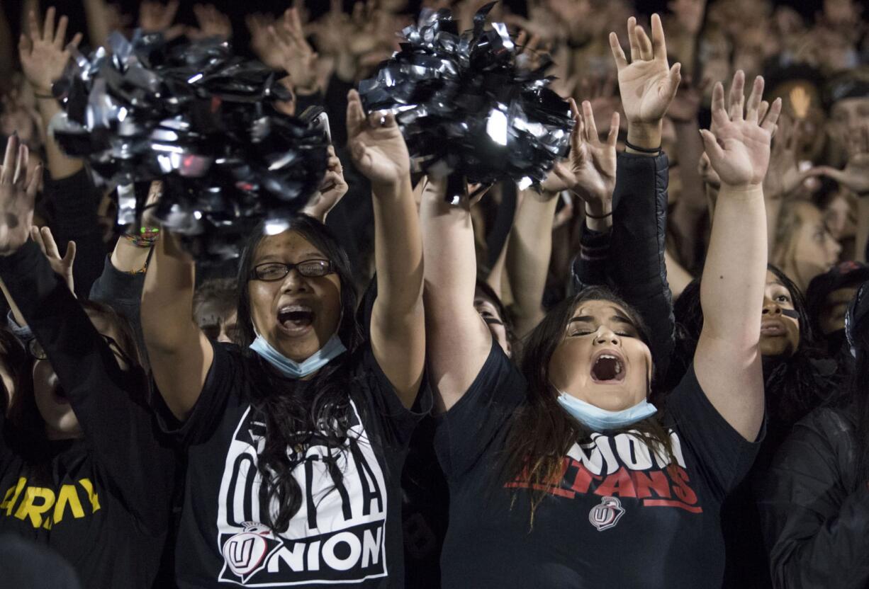 Union seniors Rosemary Hernandez, left, and Sierra Martinez, right, cheer other team during Friday night's rivalry game at Doc Harris Stadium in Camas on Oct. 27, 2017. Union defeats Camas 14-13.