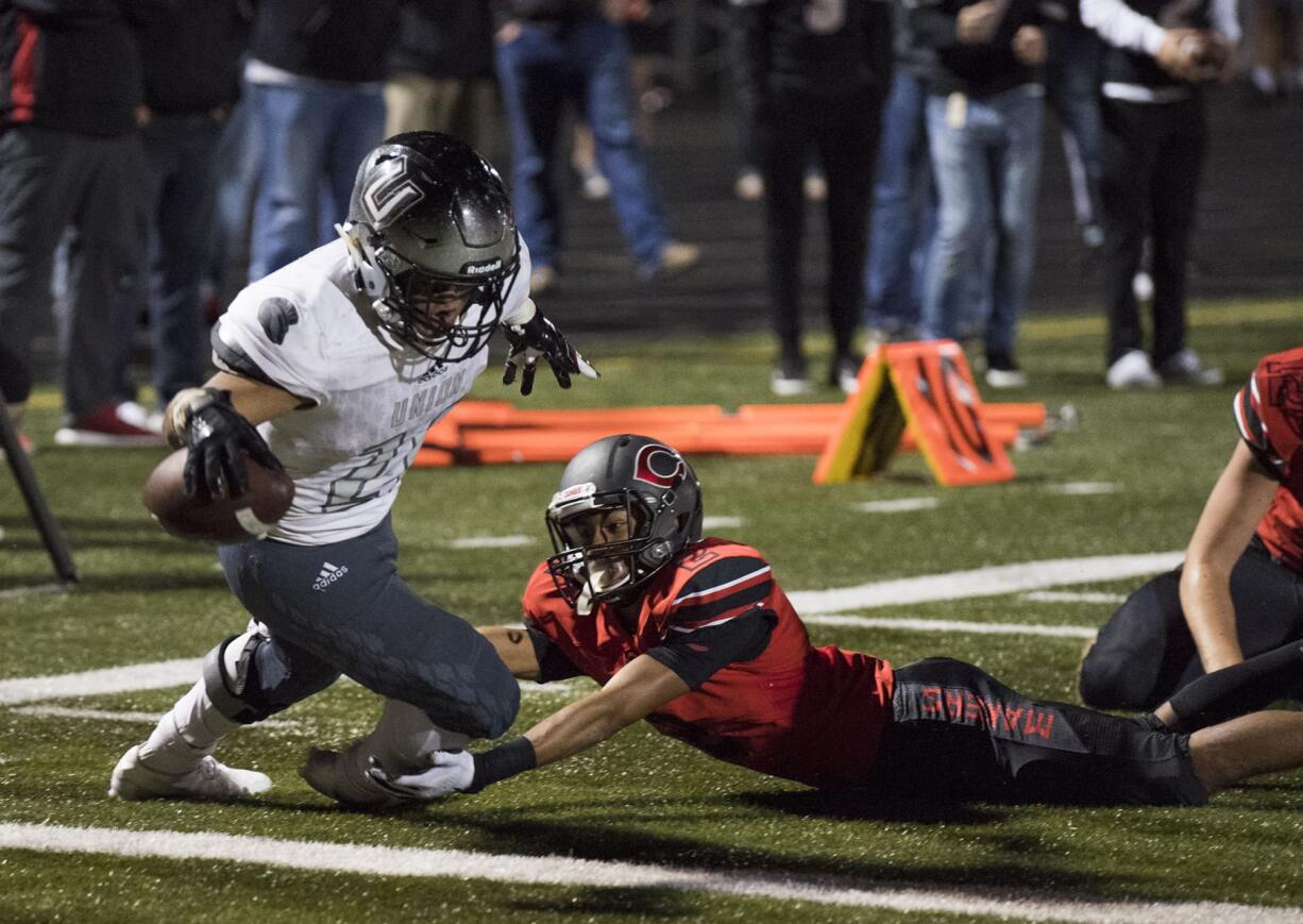 Union's Joseph Siofele (26) scores the team's second as he's brought down by Camas' Isaiah Abdul (2) during Friday night's rivalry game at Doc Harris Stadium in Camas on Oct. 27, 2017. Union defeats Camas 14-13.