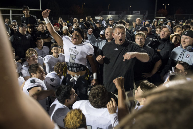 Union quarterback Lincoln Victor (5) and head coach Rory Rosenbach celebrate the victory with their team after Friday night's rivalry game against Camas at Doc Harris Stadium in Camas on Oct. 27, 2017. Union defeated Camas 14-13.