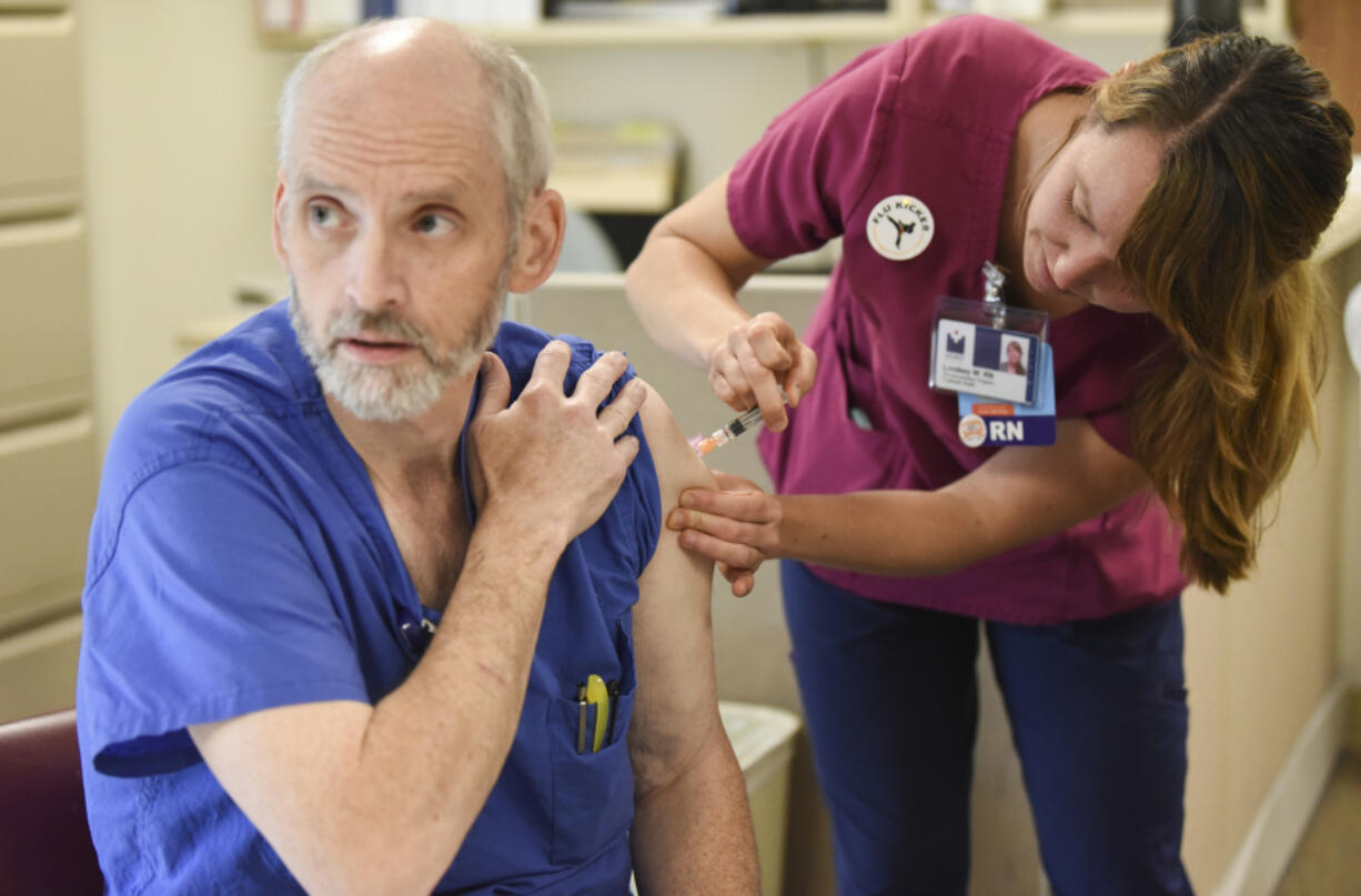 Joel Justus, a central sterile technician, receives a flu shot from Lindsey Wreden.