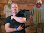 Diamondback Brewing Company co-founder Tom Foster holds Inky, a cat the brewery received from the BARCS “Working Cats” program.