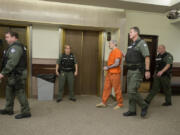 Triple-homicide suspect Brent Luyster, in orange, is surrounded by law enforcement officials as he leaves Clark County Superior Court following a hearing Oct. 6, 2017. Security for Luyster’s aggravated murder trial will be presumably tight, as it has been at most of his hearings.