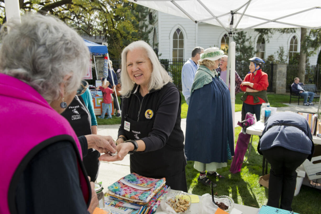 Lois Chapman, left, hands money to Jeanne Androvich, president of Friends of Ridgefield Community Library, after buying a book at a fund-raising event on Oct. 7.