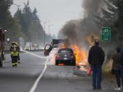 Firefighters extinguish a car on fire along State Highway 14 about a mile east of the Lieser Road exit as people look on Wednesday morning, Oct. 18, 2017. Traffic traveling in the westbound lane was backed up and routed around the scene. No injuries were reported.