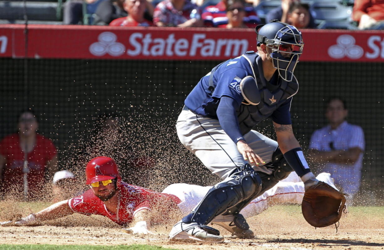 Seattle Mariners catcher Mike Marjama, right, waits for the throw as Los Angeles Angels’ Shane Robinson scores on Sunday.