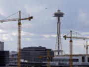 Construction cranes in the South Lake Union neighborhood stand in view of the Space Needle on Wednesday in Seattle. The city is grappling with skyrocketing rent and housing prices.