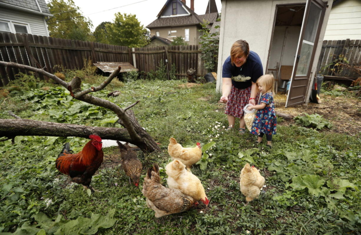 Tanya Keith and her daughter, Iolana, feed their chickens in the backyard of their home last month in Des Moines, Iowa. Keith says she warns her children not get too affectionate with the chickens.