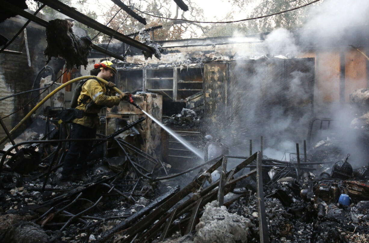 Firefighter Nick Gonzalez-Pomo, of the San Rafael Fire Department, waters down smoldering ashes on a garage Tuesday in Napa, Calif.