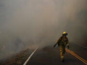 A firefighter walks along the Highway 29 as thick smoke from a wildfire fills the air Thursday, Oct. 12, 2017, near Calistoga, Calif. Communities in wildfire-prone Northern California have an array of emergency systems designed to alert residents of danger: text messages, phone calls, emails and tweets. But after days of raging blazes left at least 23 dead, authorities said those methods will be assessed after some residents complained those warnings never got through. (AP Photo/Jae C.