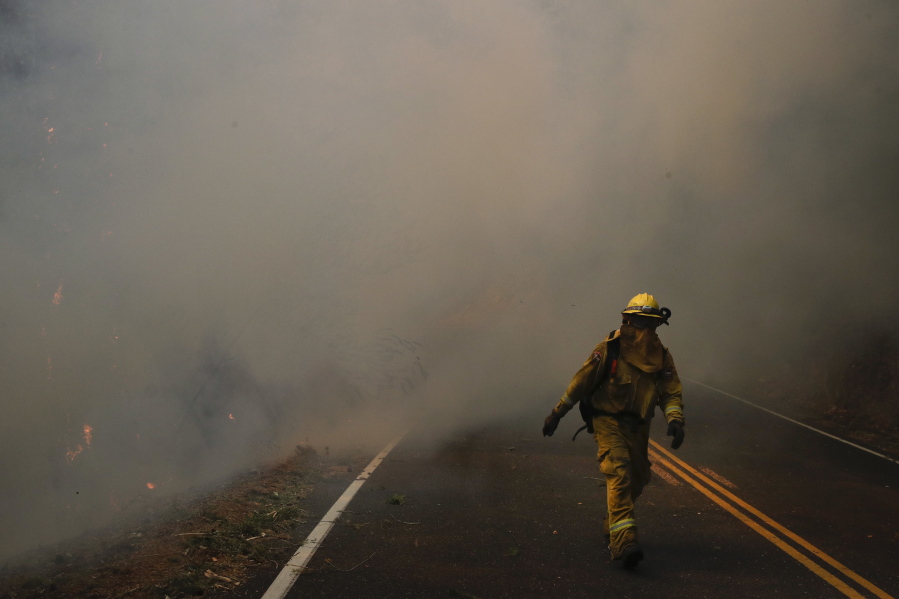 A firefighter walks along the Highway 29 as thick smoke from a wildfire fills the air Thursday, Oct. 12, 2017, near Calistoga, Calif. Communities in wildfire-prone Northern California have an array of emergency systems designed to alert residents of danger: text messages, phone calls, emails and tweets. But after days of raging blazes left at least 23 dead, authorities said those methods will be assessed after some residents complained those warnings never got through. (AP Photo/Jae C.