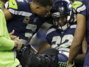 Seattle Seahawks quarterback Russell Wilson, left, comforts running back Chris Carson before Carson is taken away on a cart Sunday against the Indianapolis Colts.