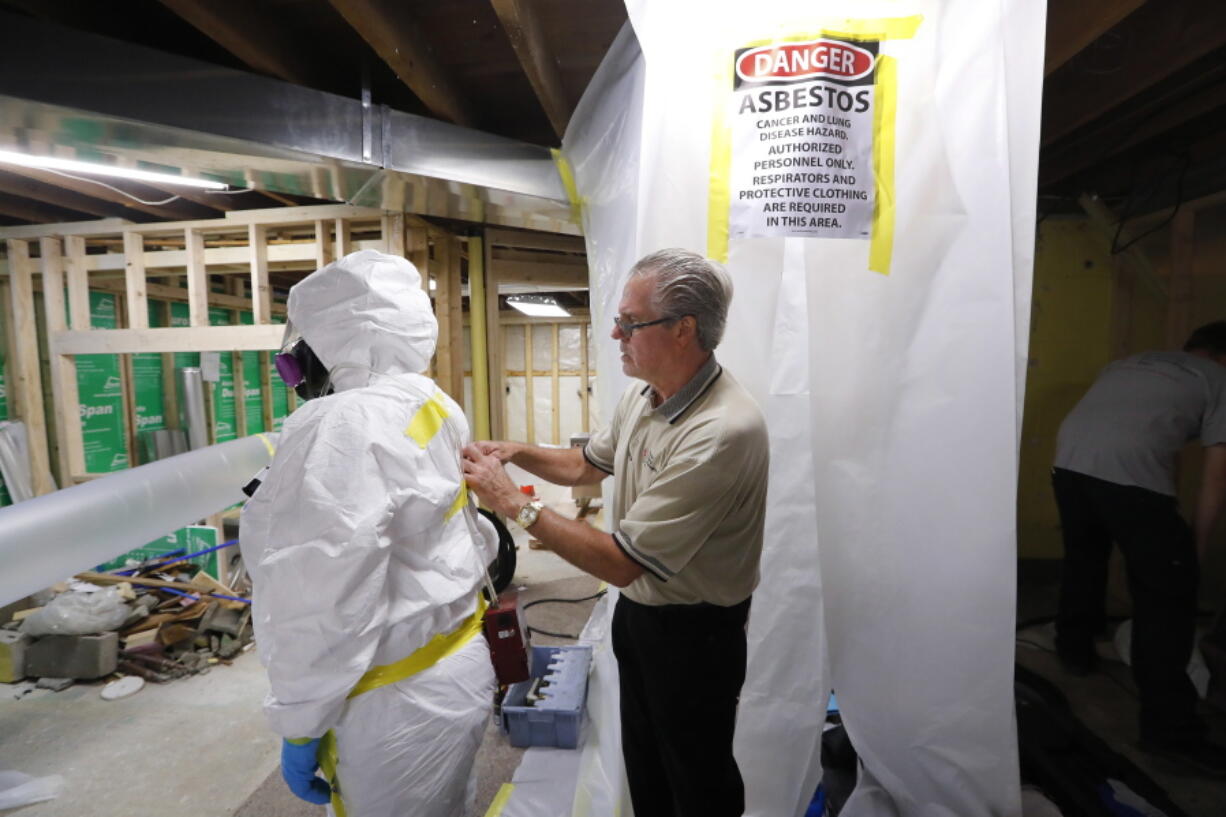 George Riegel, Jr., M.D., right, owner of Asbestos Removal Technologies Inc., helps prepare a personal air monitor on job forman Megan Eberhart before asbestos abatement in Howell, Mich. Congress ordered the EPA review last year to gauge risks of asbestos and nine other highly toxic substances and find better ways to manage them for public safety.