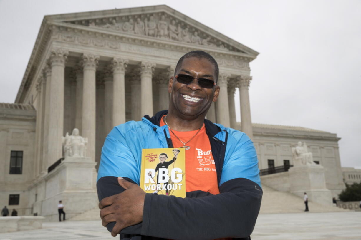 In this Oct. 13, 2017, photo, Bryant Johnson, personal trainer for Supreme Court Justice Ruth Bader Ginsburg poses in Washington, with his new book, “The RBG Workout: How She Stays Strong ... and You Can Too!” Besides the 84-year-old Ginsberg, Johnson, who now also trains Justice Stephen Breyer and Justice Elena Kagan. Johnson says he hopes the book will help convince people: ‘ÄúYou’Äôre never too old to do something.’Äù (AP Photo/J.