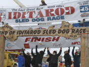 Volunteers help raise the Iditarod finishers banner at the burled arch finish line in Nome, Alaska, on March 16, 2015.