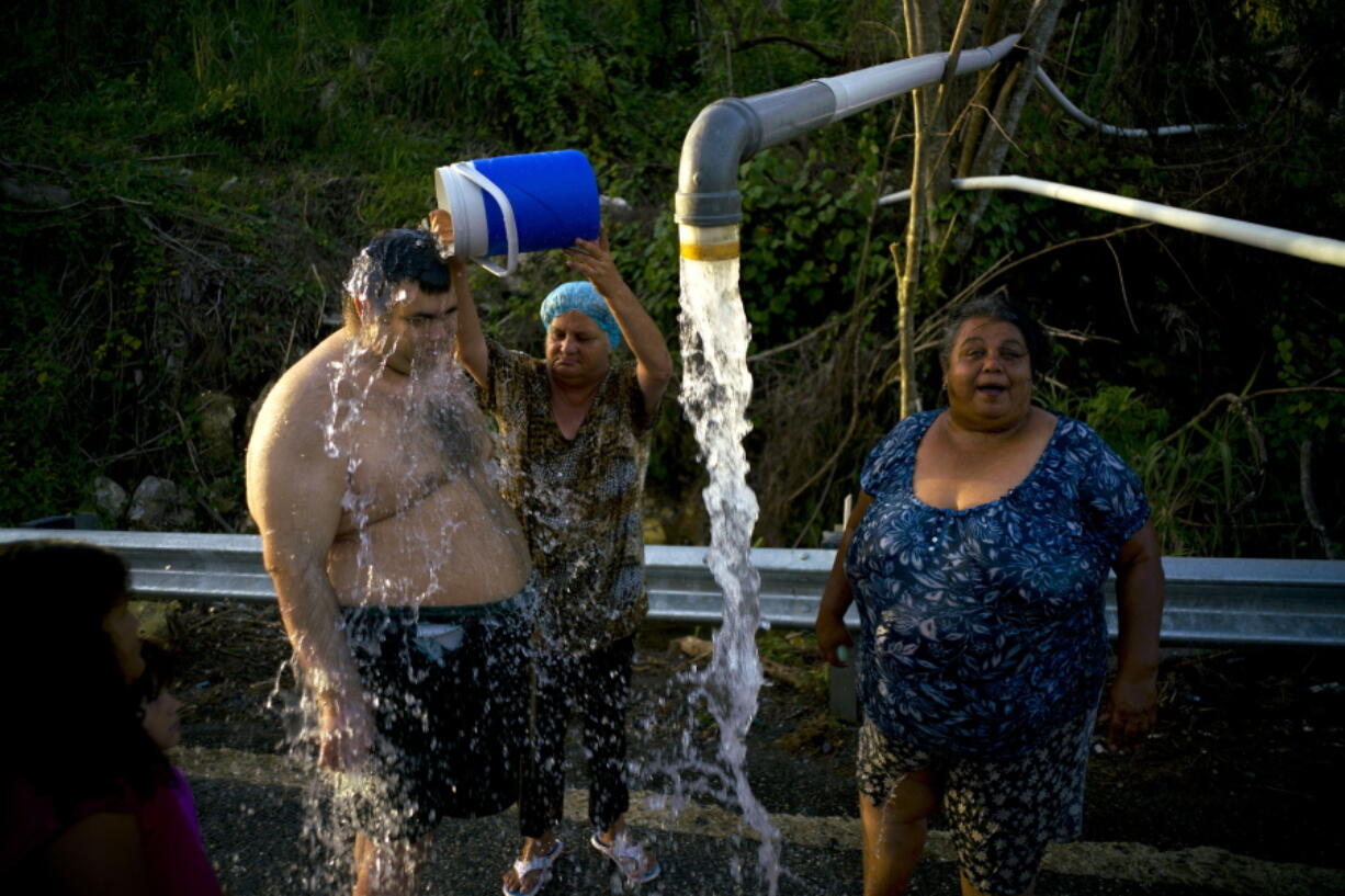 People affected by Hurricane Maria bathe in water piped from a mountain creek, in Utuado, Puerto Rico, on Saturday. Raw sewage is pouring into the rivers and reservoirs of Puerto Rico in the aftermath of Hurricane Maria. Puerto Ricans without running water are bathing and washing their clothes in contaminated streams. At least four people have died of diseases caught from dirty water.