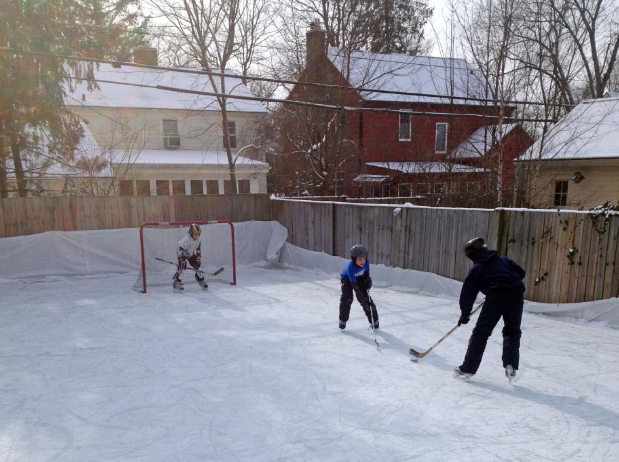 Members of the Rubin family play hockey on their backyard ice rink in the Burns Park neighborhood of Ann Arbor, Mich.