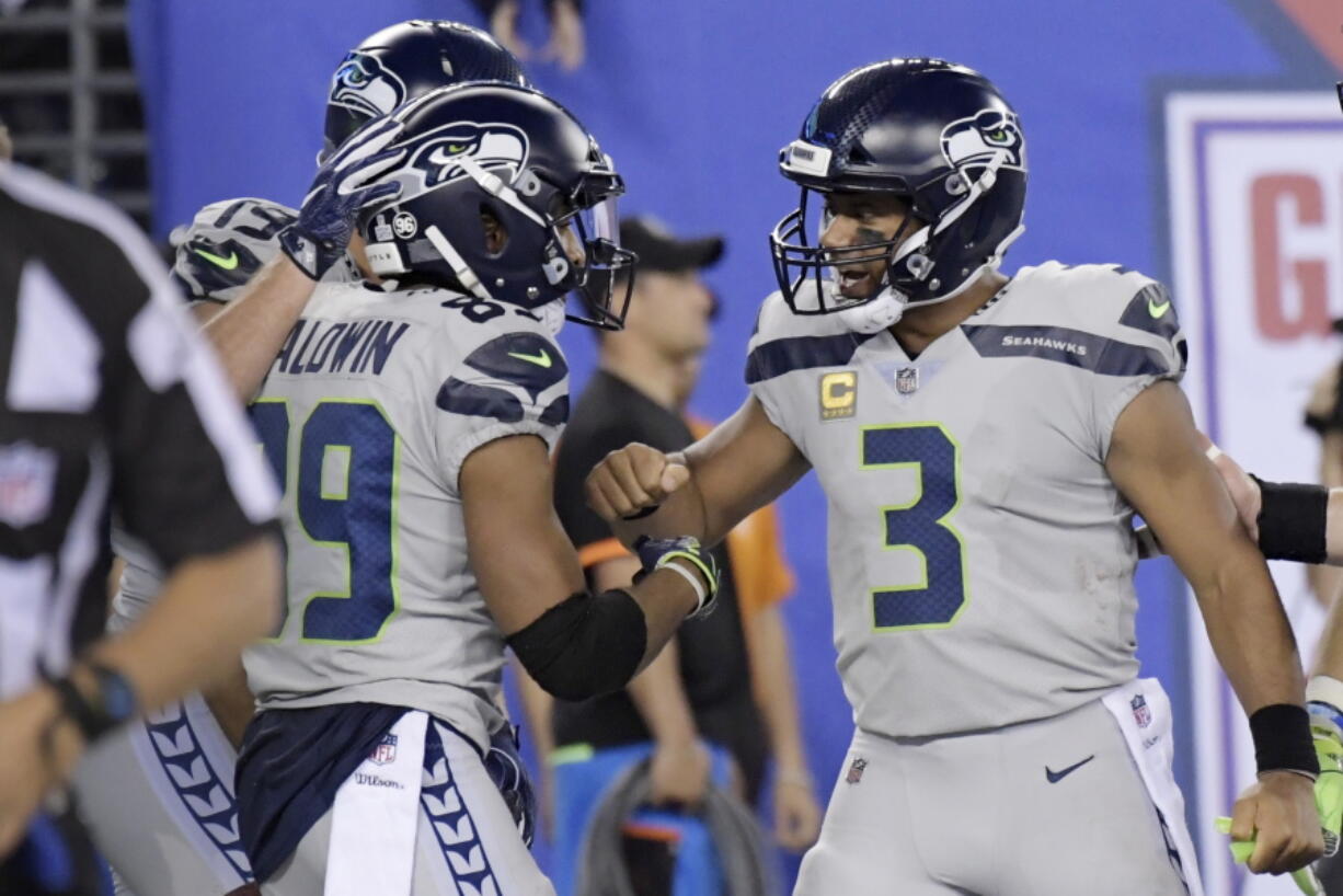 Seattle Seahawks quarterback Russell Wilson, right, celebrates with Doug Baldwin after scoring a touchdown during the second half of an NFL football game against the New York Giants, Sunday, Oct. 22, 2017, in East Rutherford, N.J.