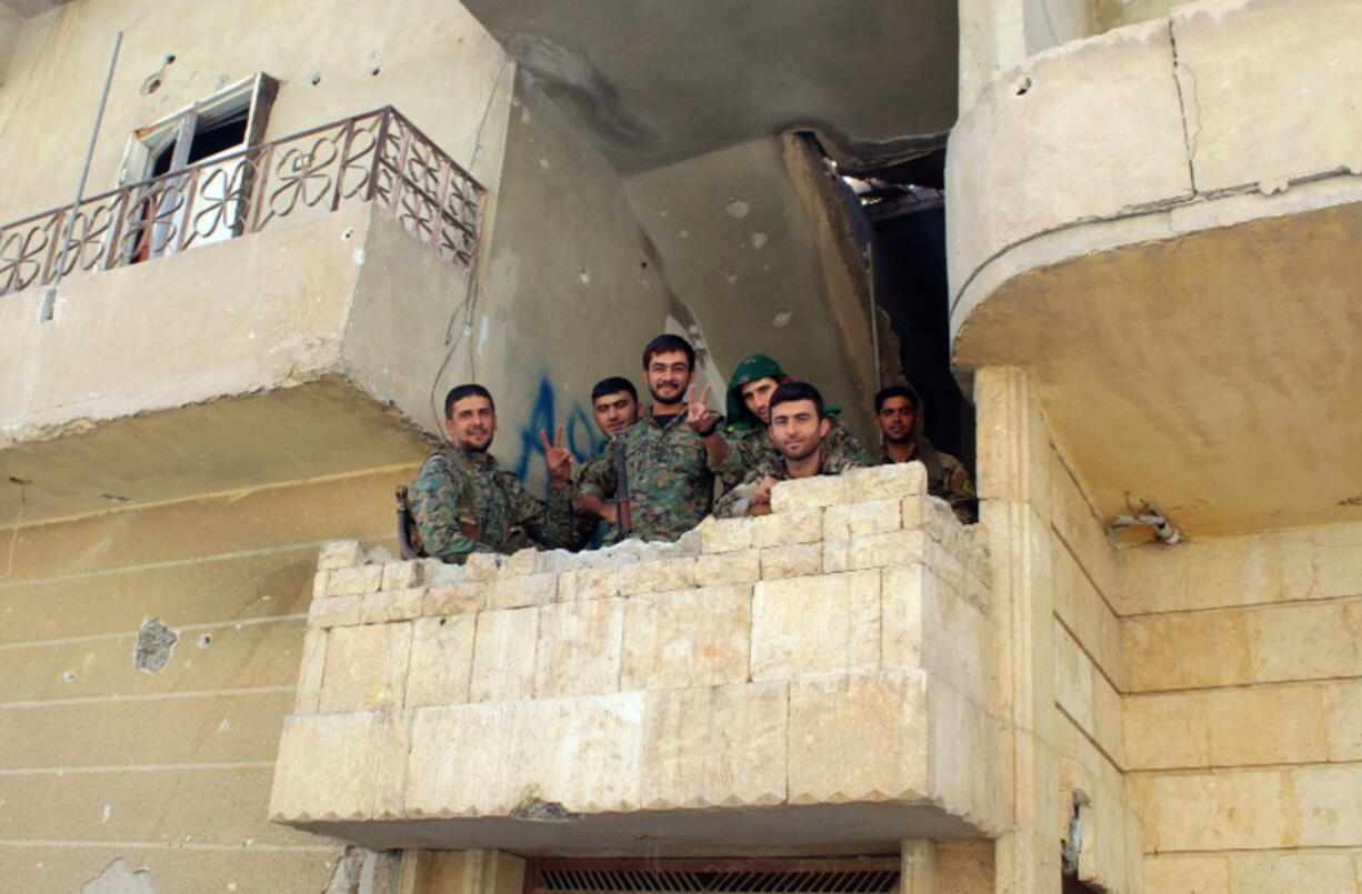 In this picture taken on Monday Oct. 16, 2017 and provided by The Syrian Democratic Forces (SDF), a U.S.-backed Syrian Kurdish forces outlet that is consistent with independent AP reporting, shows Syrian Democratic Forces (SDF) fighters, flash victory signs at the front line where they battle against the Islamic State militants, in Raqqa, Syria. The U.S-backed Syrian forces battling the Islamic State group in Syria say Raqqa’s national hospital, one of the militants’ last holdouts in city has been captured.