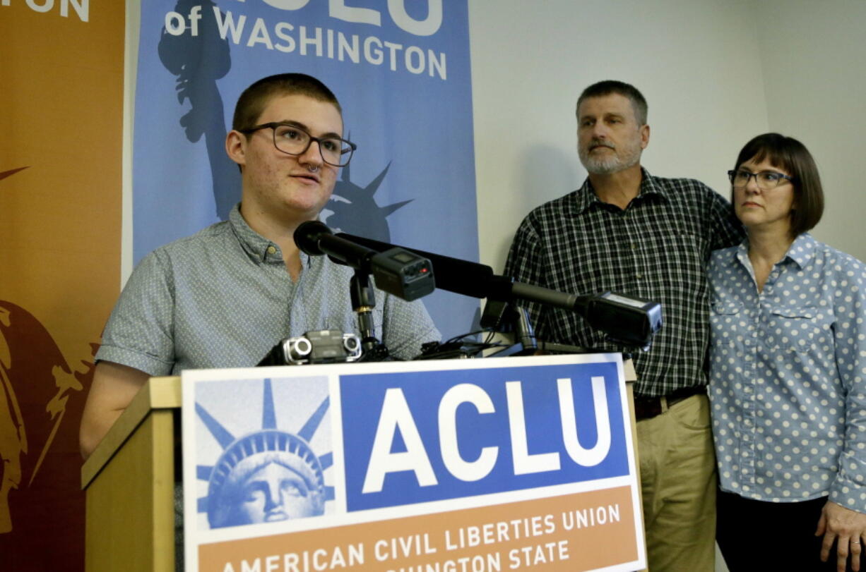 Paxton Enstad, left, speaks at a news conference about a lawsuit filed over refusal by an insurance plan to cover his gender-reassignment surgery as his parents, Cheryl and Mark Enstad, look on Thursday in Seattle.