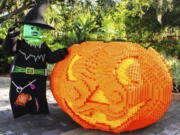 A giant pumpkin made from Legos at Legoland in Winter Haven, Fla., with a costumed greeter standing nearby.