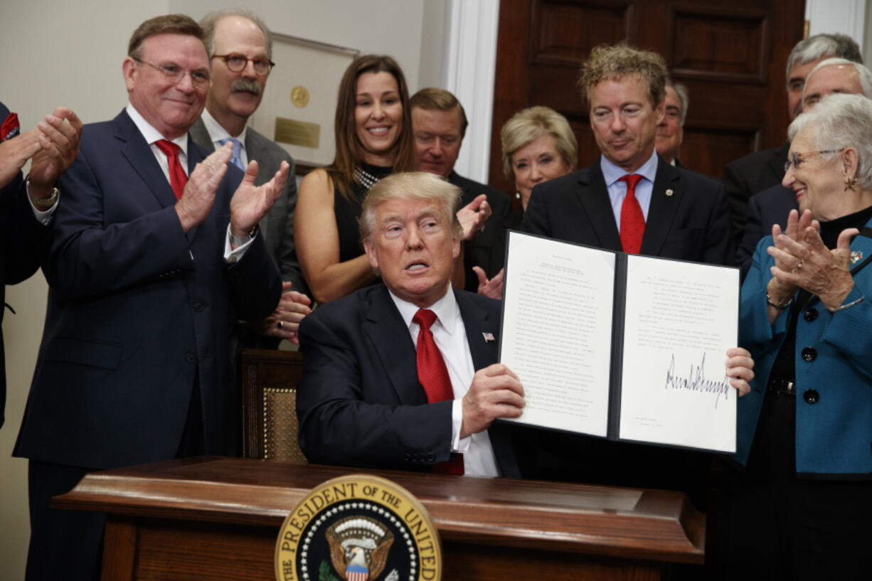 President Donald Trump shows an executive order on health care that he signed in the Roosevelt Room of the White House, Thursday in Washington.