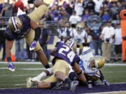 UCLA’s Jordan Wilson, right scores against Washington in the first half of an NCAA college football game Saturday, Oct. 28, 2017, in Seattle.