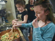 Maddie Wallingford, 9, right, tries a piece of frozen corn while making shepherd’s pie with her sister, 6-year-old Hazel, and mom, Mari, at their Vancouver home Tuesday evening. Maddie used to be an extremely picky eater until she went through Innovative Services NW’s food therapy program.