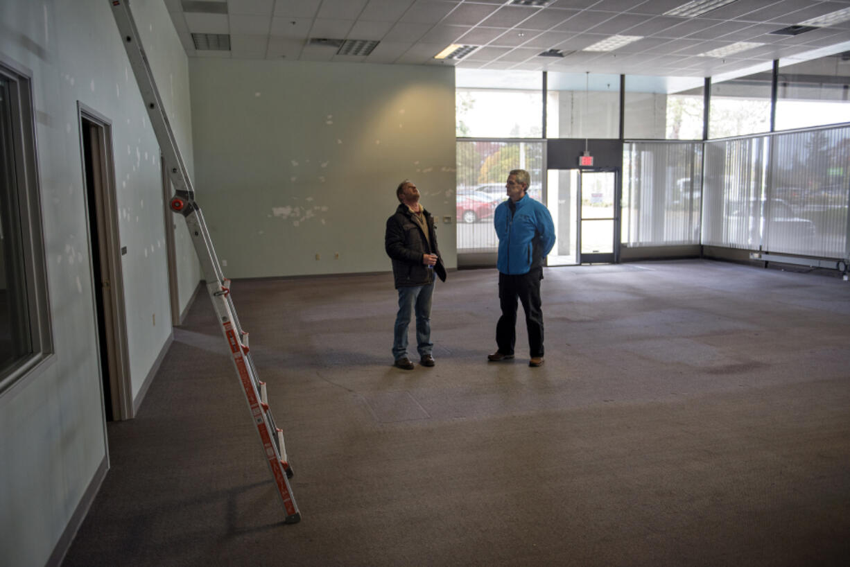 Construction project manager Chris Dery with the Vancouver Housing Authority, left, and housing rehab specialist Craig Frantz with the city of Vancouver, right, look over the front area of the former Fish and Wildlife Building in Vancouver on Wednesday, a space that the city intends to use as a day center for homeless people.