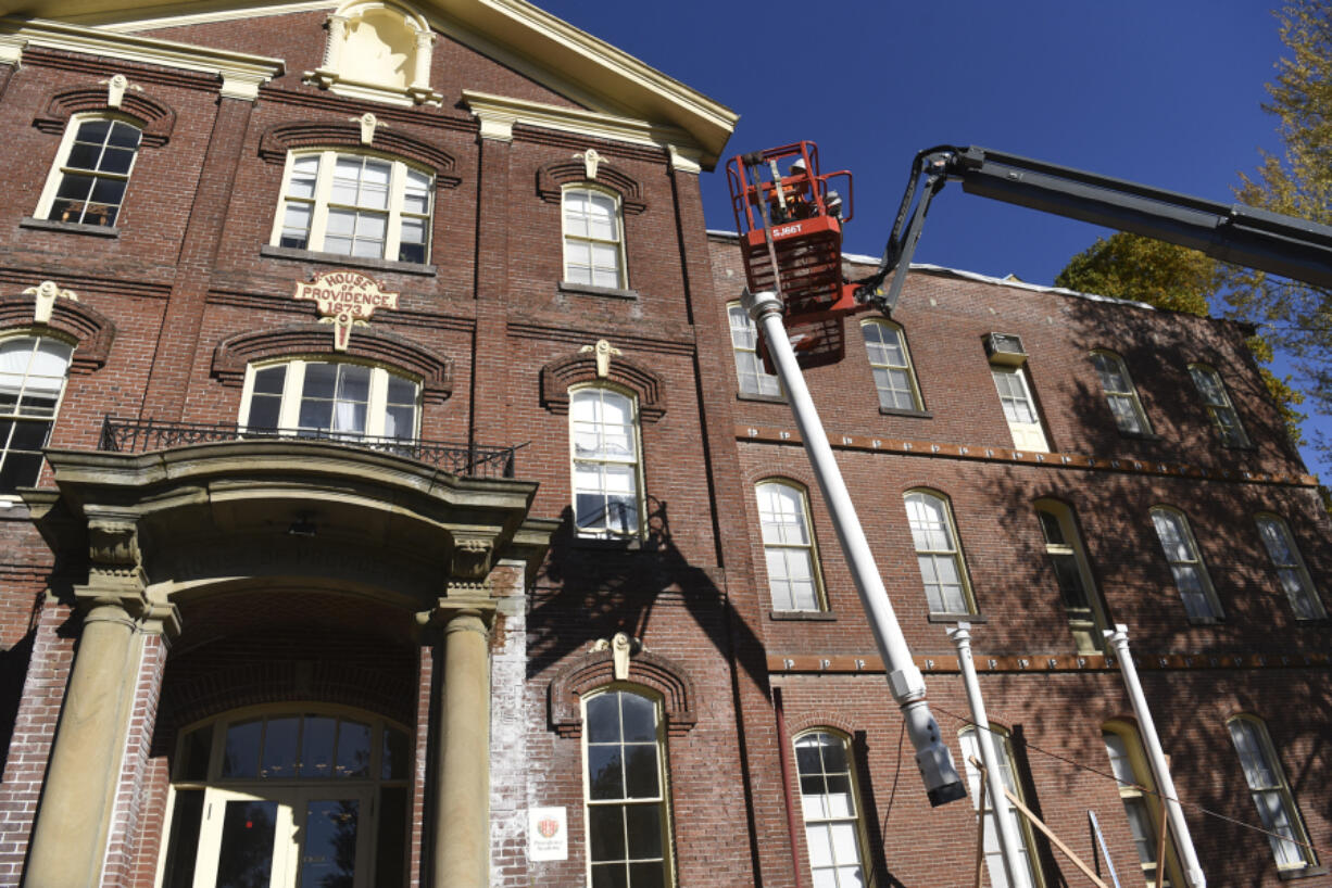 A pillar is hoisted into place as workers rebuild the ground-floor porch Tuesday at Providence Academy. The Historic Trust is renovating the landmark at 400 E. Evergreen Blvd.