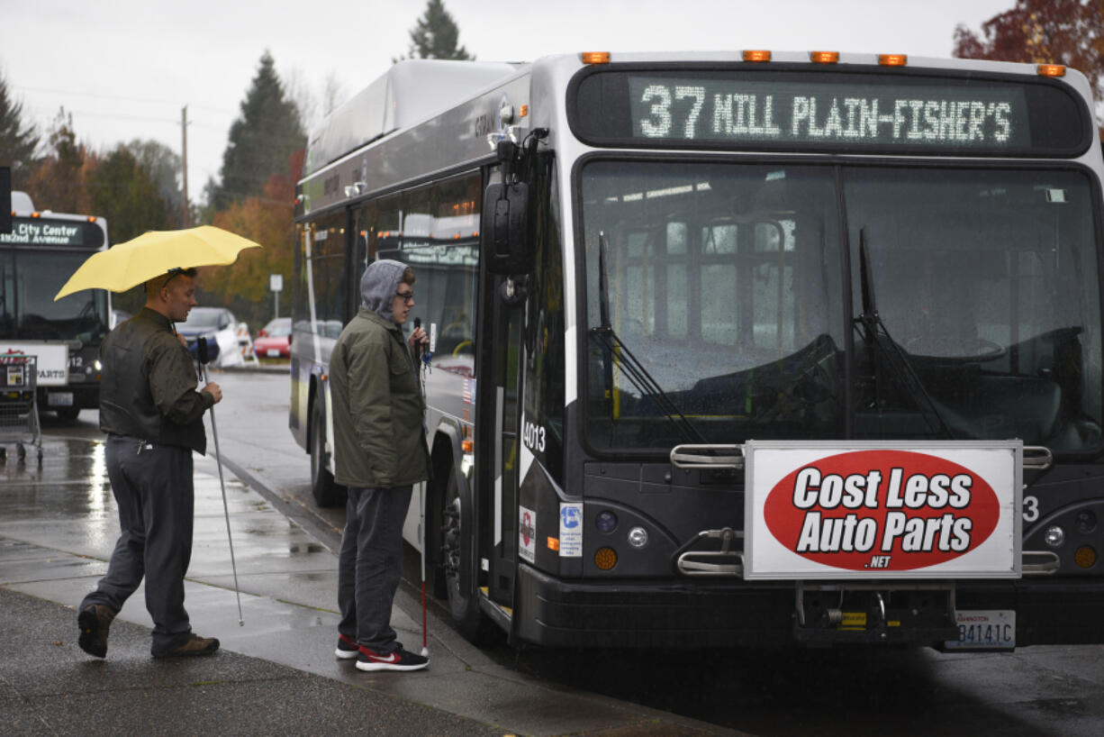 Passengers board a C-Tran bus Thursday at Fisher’s Landing Transit Center. The advertisements mounted on some of C-Tran’s fleet will be removed in the near future.