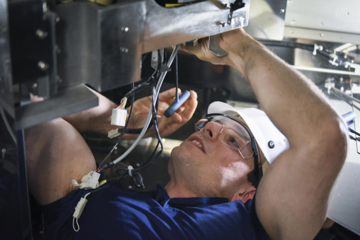 Shane Hoffman, a U.S. Marine Corps veteran, works on removing the motor from a wafer transfer robot in a vertical diffusion furnace at Kokusai in Vancouver. Hoffman is one of many military veterans hired by the company as it looks to set record revenues this year.