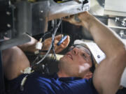 Shane Hoffman, a U.S. Marine Corps veteran, works on removing the motor from a wafer transfer robot in a vertical diffusion furnace at Kokusai in Vancouver. Hoffman is one of many military veterans hired by the company as it looks to set record revenues this year.