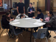 Central Park: Skyview High School senior Carson Mowrer, standing left, and Vancouver iTech Preparatory senior Sasha Thomas, standing right, volunteered at the Washington State School for the Blind to teach students how to solve a Rubik’s Cube they created that replaces colors with tactile surfaces such as Velcro.