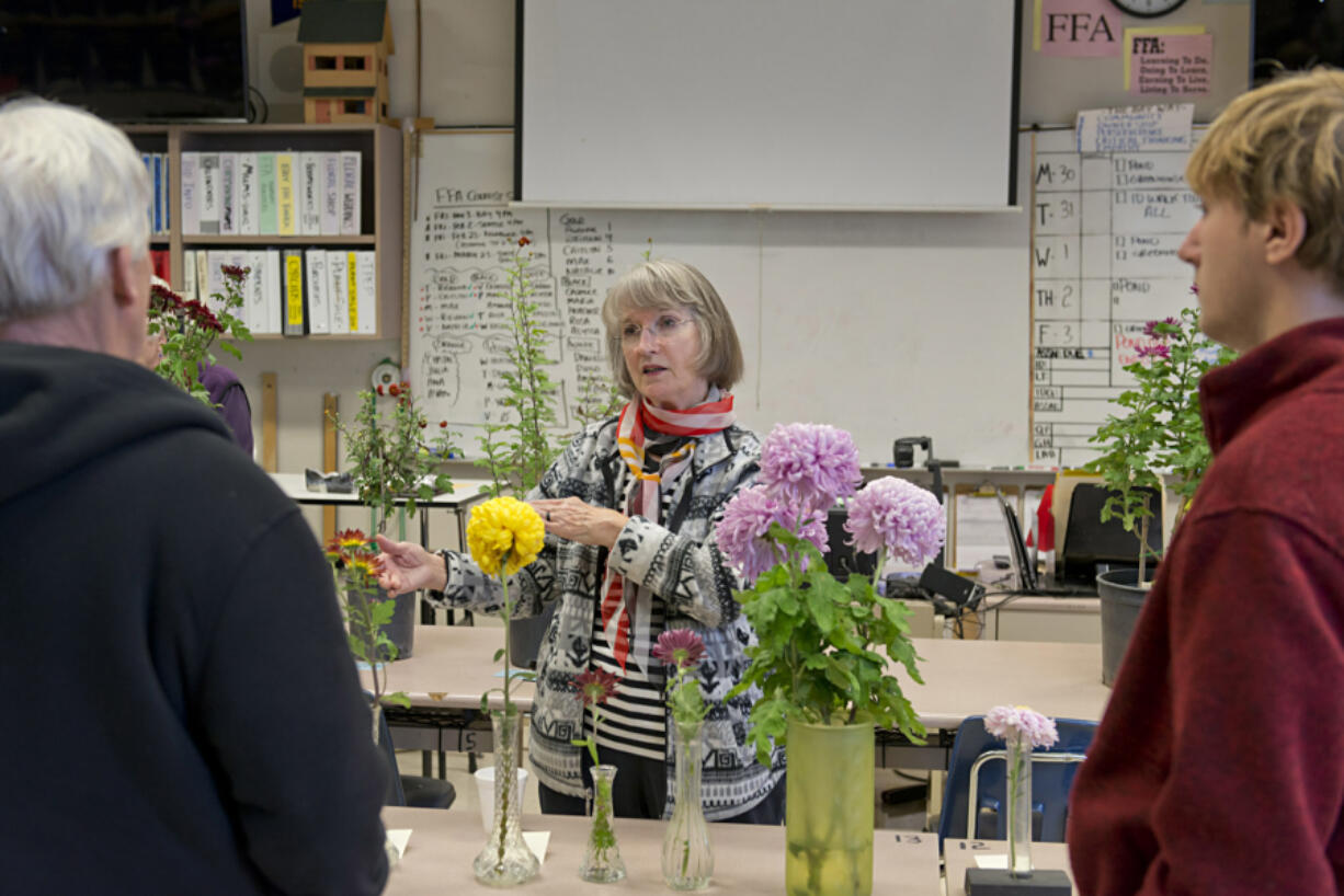 Elizabeth Adamson, Bill Wastradowski, left, and Micah Black talk shop about chrysanthemums Sunday at Hudson’s Bay High School, during the Vancouver Chrysanthemum Society’s annual flower show.