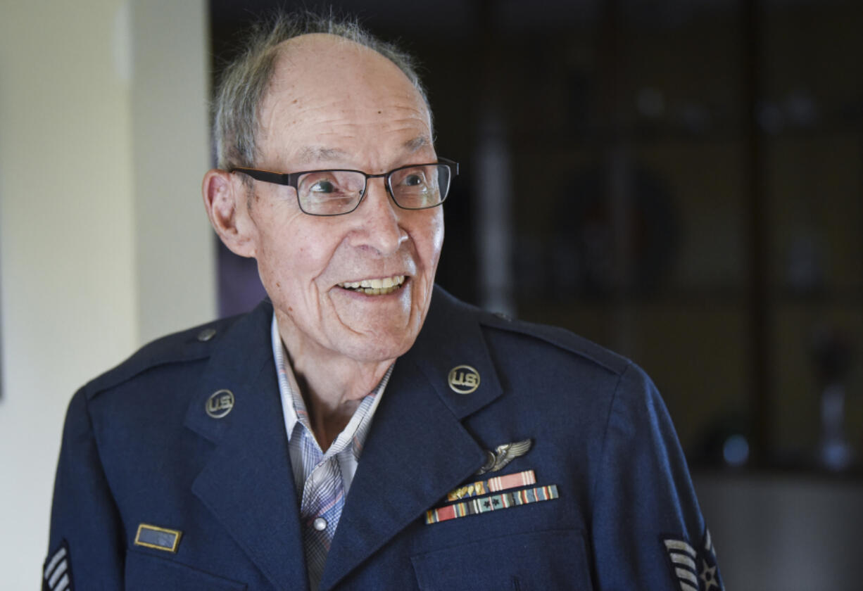 Phil Azure, a veteran of two wars, tries on the Air Force uniform jacket that represents his Korean War service. He was an Army airman during World War II. Below: Waist gunner Sam Lavoi, from left, radio operator Tom Demery, ball turret gunner Clement Bradbury, pilot Bob Millar, navigator Henry Nolan, engineer Evan House and tail gunner Phil Azure are pictured in front of a B-17 bomber in 1944. The photo is among the World War II keepsakes at Azure’s home in Vancouver.