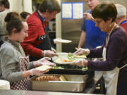 Volunteers Lauren Naughton, left, and Linda Meade, prepare dinner plates for the weekly Frassati supper served at the Proto-Cathedral of St. James the Greater in downtown Vancouver.