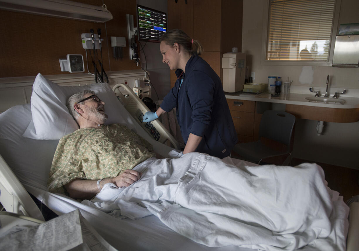 Vancouver resident William Gilbert, left, shares a moment with registered nurse Mandy Herrera during his stay Nov. 13 at Legacy Salmon Creek Medical Center. Nurses in two units of the hospital implemented a no-cellphone policy in patient care areas that is now spreading to the rest of the hospital. Patient satisfaction scores have increased since the policy was implemented.