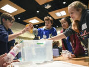 Our Lady of Lourdes Catholic School sixth-graders, from left, Andrew Dickson, Gabe DaSilva, Erin Chan and Alyssa Mancuso dunk plastic items into a tub of water to determine which ones float and which ones sink in a lesson about the ocean and reducing plastic consumption Thursday during the Clark County Green Schools summit at Clark College.