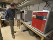 Marc Kramer, assistant professor of environmental chemistry at Washington State University Vancouver, looks over an isotope-ratio mass spectrometer in a lab on campus. Kramer has discovered that vast amounts of carbon can be stored by soil minerals more that a foot below the surface.