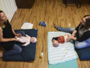 Infant-massage educator Regina Greenwood, left, uses a doll to demonstrate massage strokes that Kelly Griffith, right, can use on her son, 4-month-old Brennon, during an infant-massage session on Nov. 15 at Greenwood’s Vancouver home. Greenwood has been teaching parents how to connect with their babies through massage for the last two years.