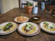 Rice and refried beans, top center, a lamb barbacoa taco, bottom left, carnitas caramelized pork taco and a rajas de pablano taco, the seasonal vegetable option, at Little Conejo in Vancouver.